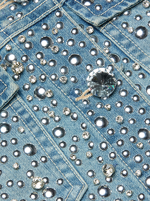 Close-up of the Vangie Embellished Jean Jacket, featuring blue denim decorated with round and faceted silver and clear rhinestones that create a sparkling, textured look. Visible pocket seams and stitching add extra detail to this standout piece.