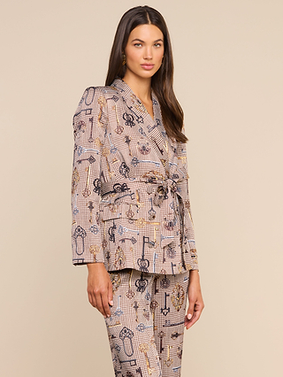 A woman wears the Aven Wrap Blazer, a modern suiting ensemble in beige, black, and gold with a stylish wrap-front and matching belt. She has long brown hair and stands confidently against a plain light background, looking at the camera.