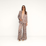 A woman stands confidently against a plain white background, wearing the Aven Wrap Blazer in a brown houndstooth pattern, paired with matching wide-leg pants, a tan top, heels, and sunglasses.