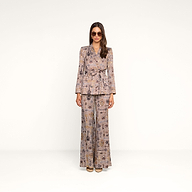 A woman wearing sunglasses and a patterned brown houndstooth pantsuit with the Aven Wrap Blazer stands against a plain white background, facing the camera with her arms at her sides.