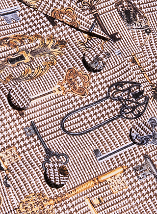 Aven Wrap Blazer: This chic wrap-front blazer features a brown houndstooth patterned fabric adorned with decorative vintage key illustrations in gold, black, and bronze tones—perfect for effortlessly elevating modern suiting.