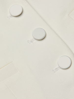 Close-up of the Tomi Vest in off-white fabric, featuring a satin lapel, three large round white buttons, and a small left pocket. Visible stitching and buttonholes add detail to the smooth material.