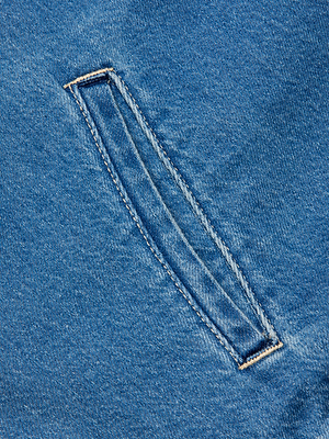 Close-up of the Dunia Jean Jacket in blue cotton denim, showcasing a single welt pocket with visible stitching—ideal for a lightweight, relaxed-fit style.