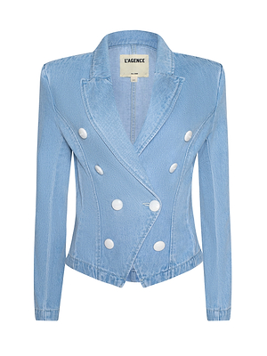 The Emerson Structured Blazer is a light blue denim jacket featuring a sculpted fit, long sleeves, wide lapels, and six large white front buttons. Inside, the label reads “L’AGENCE.”.