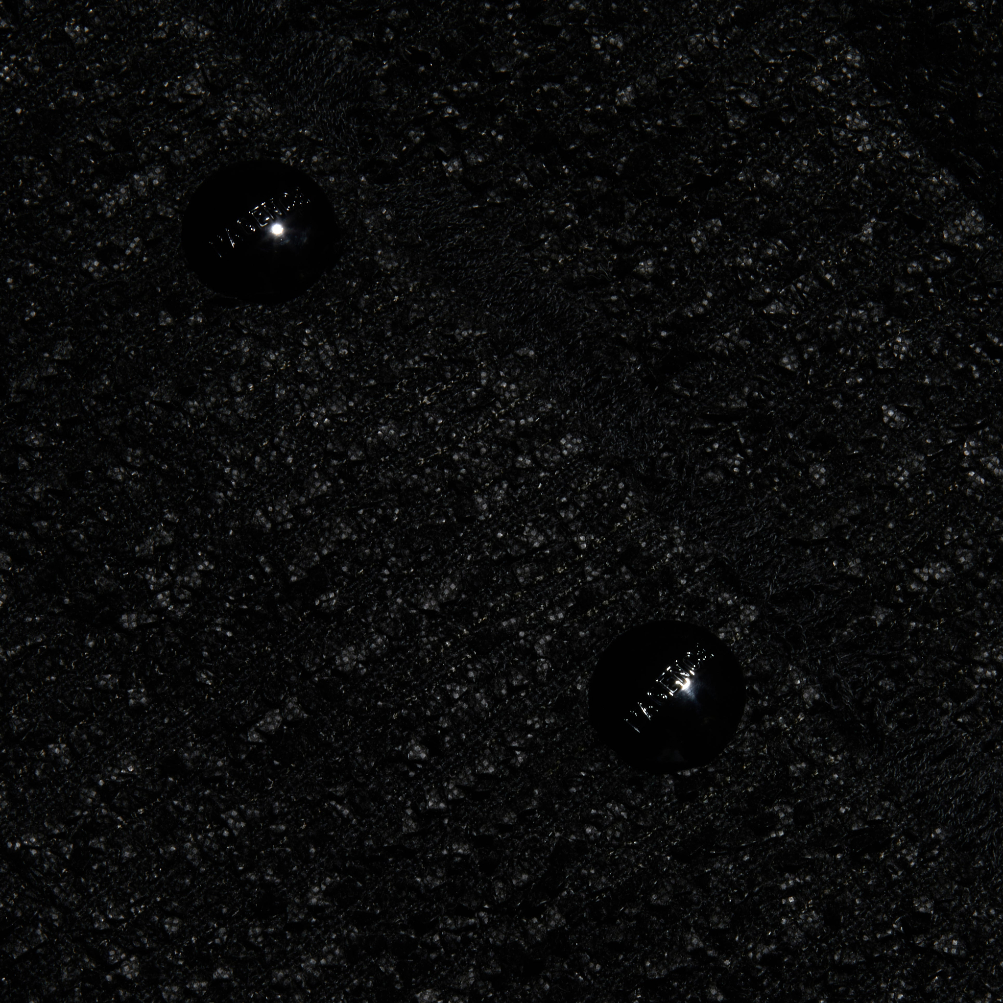 Close-up of the Nerina Tweed Blazer’s textured black tweed fabric featuring two shiny black buttons sewn in a vertical arrangement near the center.