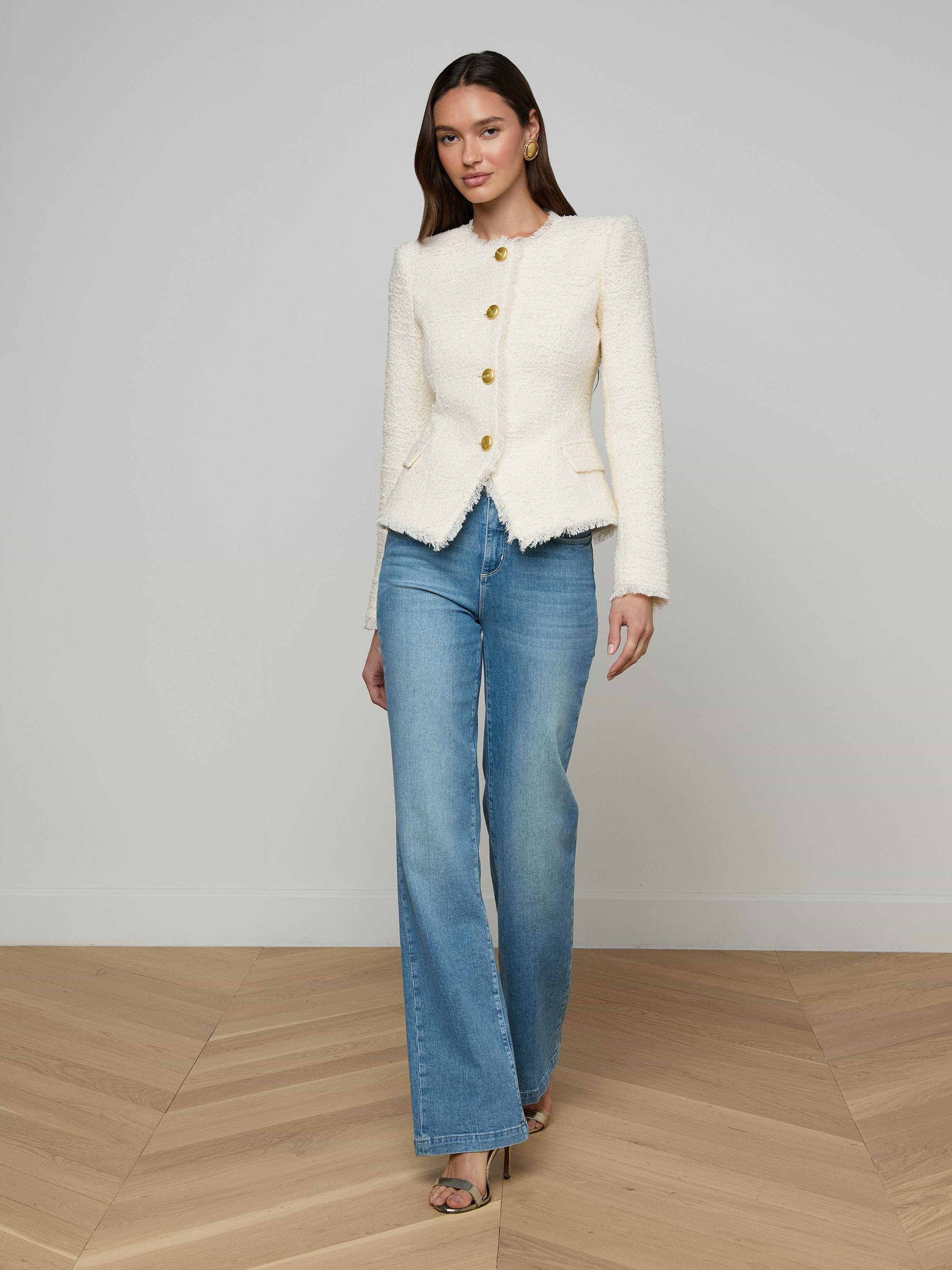 A woman wearing the Nerina Tweed Blazer, styled with blue wide-leg jeans and black heels, stands against a plain white background.
