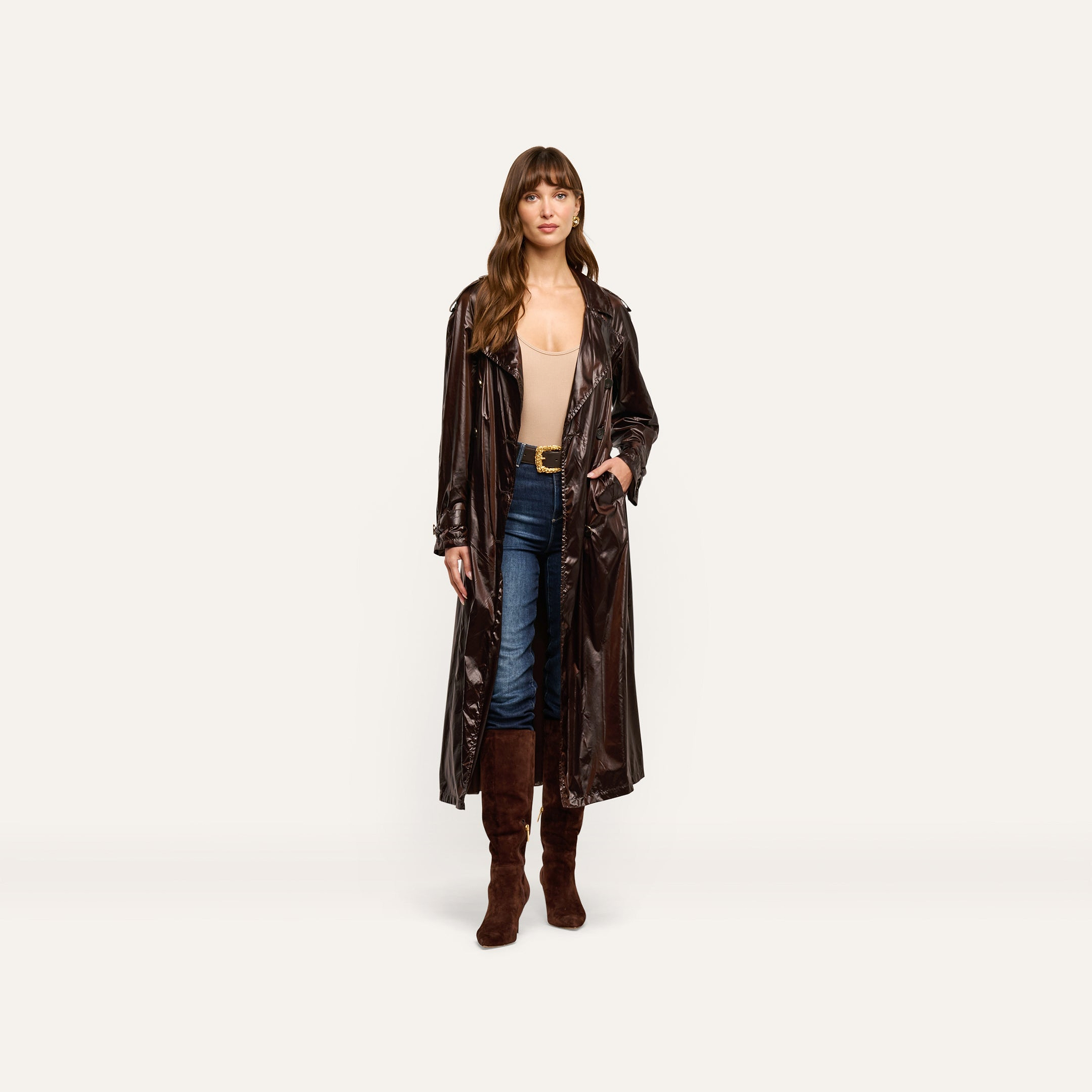 A person wearing a dark-brown Brinley Nylon Trench Coat over a beige bodysuit, blue jeans, and brown knee-high boots.