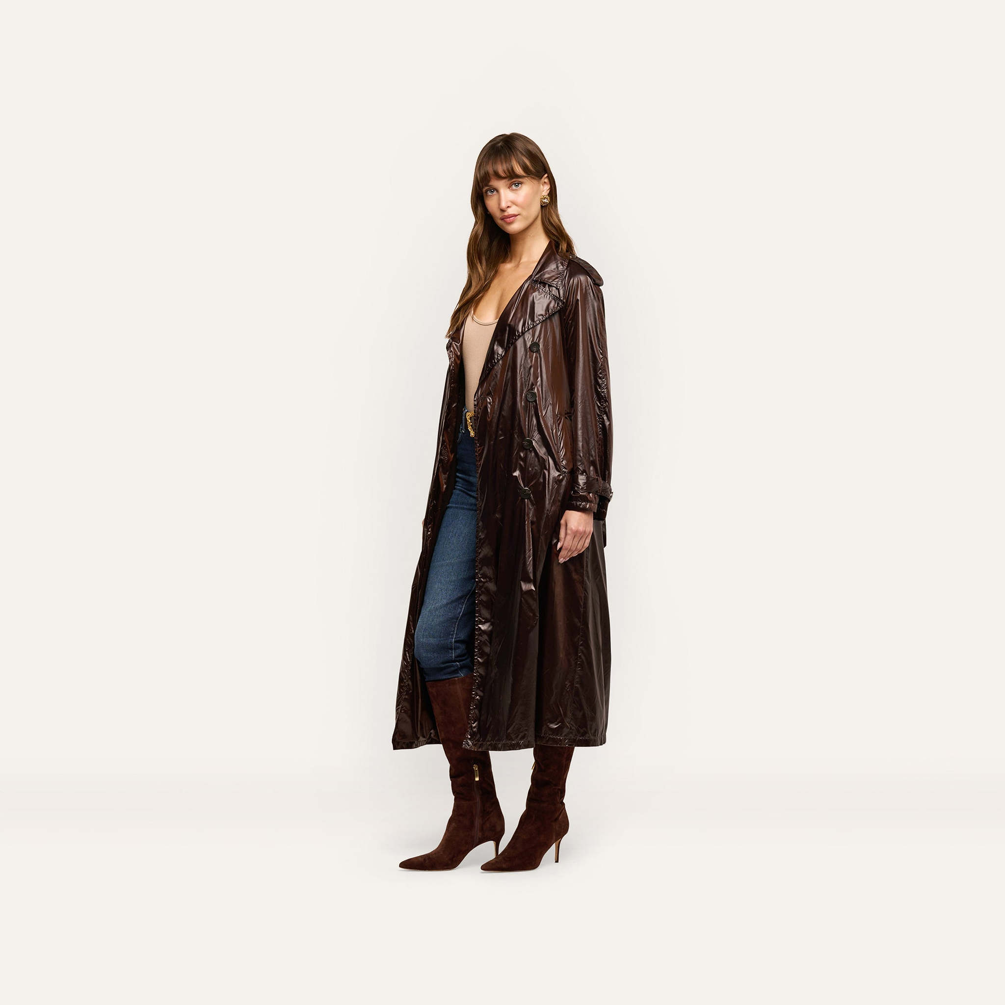 A person wearing an oversized dark brown Brinley Nylon Trench Coat over a beige top, blue jeans, and brown suede heeled boots.
