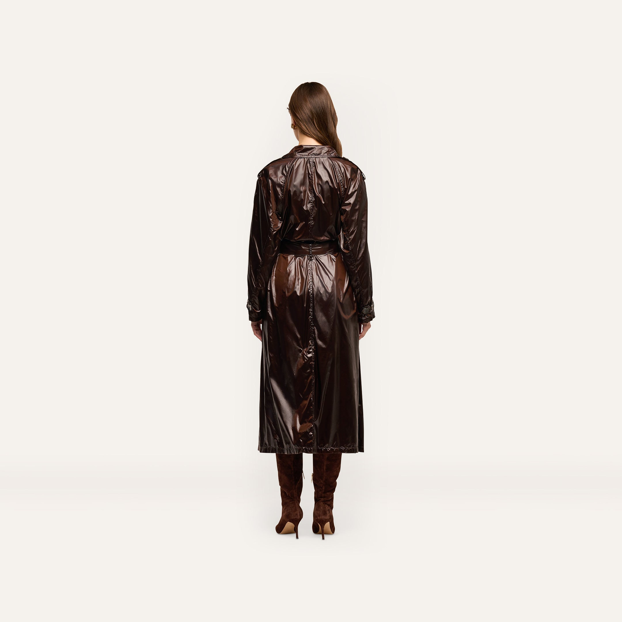 Back view of a person wearing an oversized, double-breasted dark brown Brinley Nylon Trench Coat and knee-high heeled boots.