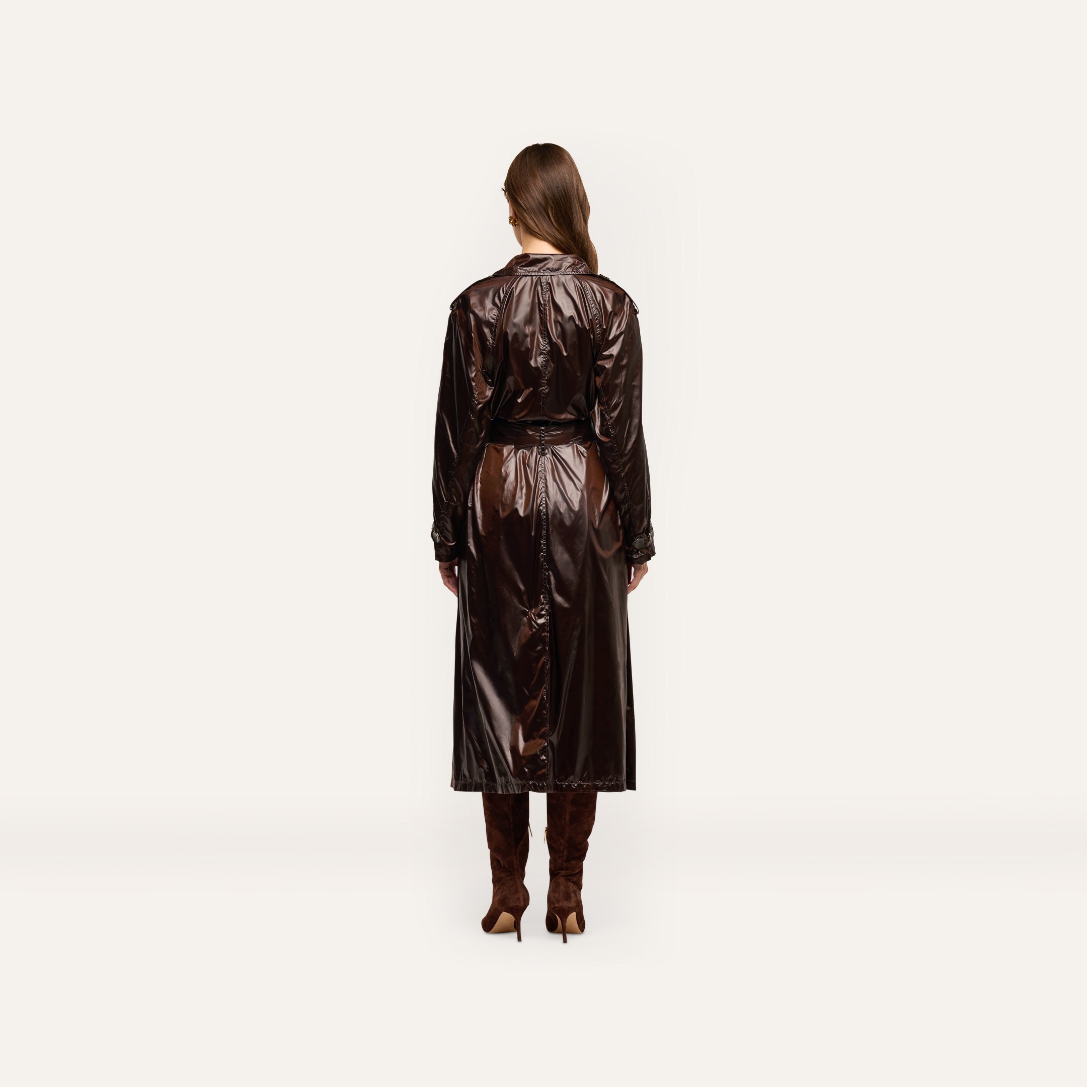 Back view of a person wearing an oversized, double-breasted dark brown Brinley Nylon Trench Coat and knee-high heeled boots.