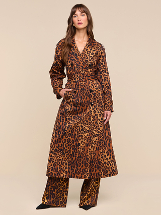 A person stands wearing the Brinley Oversized Trench Coat, styled with matching wide-legged leopard print pants and black shoes, posing against a plain beige background.