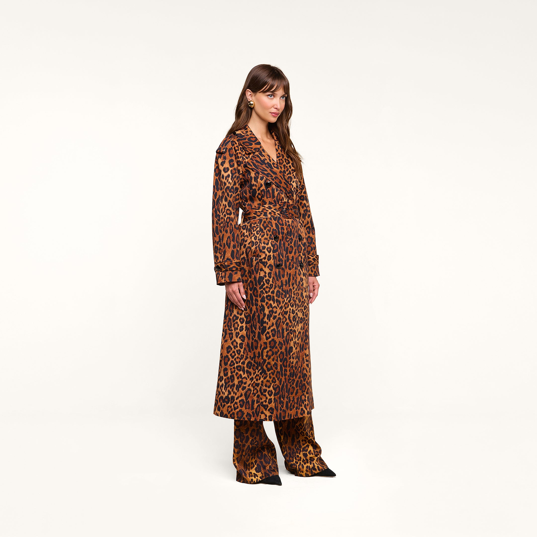 A woman stands against a plain background, wearing the Brinley Oversized Trench Coat in a leopard print with matching leopard-print pants and black pointed shoes.