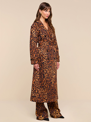 A woman stands against a beige background, wearing the Brinley Oversized Trench Coat over matching pants and black pointed shoes. She faces slightly to the right with her hands by her sides.