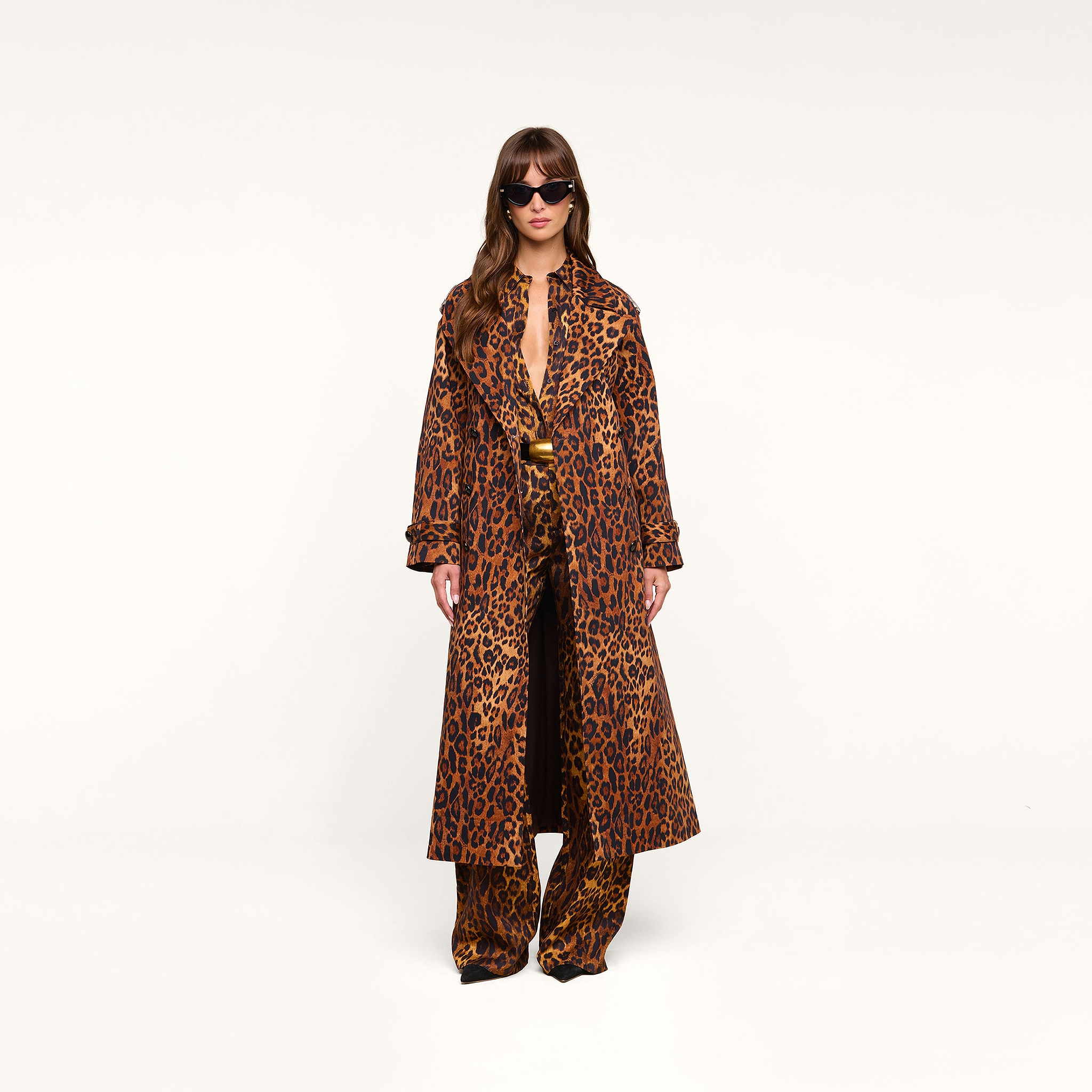A person wearing sunglasses and the Brinley Oversized Trench Coat, styled with matching leopard print pants, stands against a plain white background.