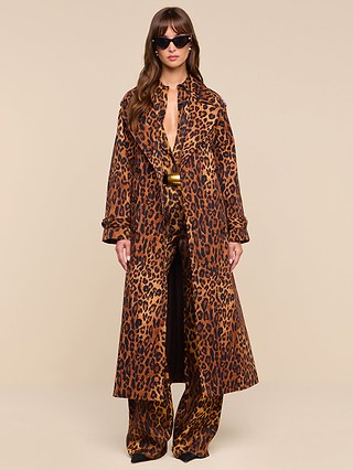 A woman wearing sunglasses and the Brinley Oversized Trench Coat with matching pants stands against a beige background, facing forward with her hands by her sides.
