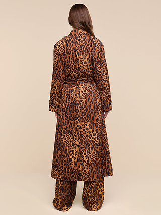 A person stands with their back to the camera, wearing the Brinley Oversized Trench Coat in a long, leopard print style paired with matching wide-legged pants. Their brown hair falls down their back against a plain beige background.