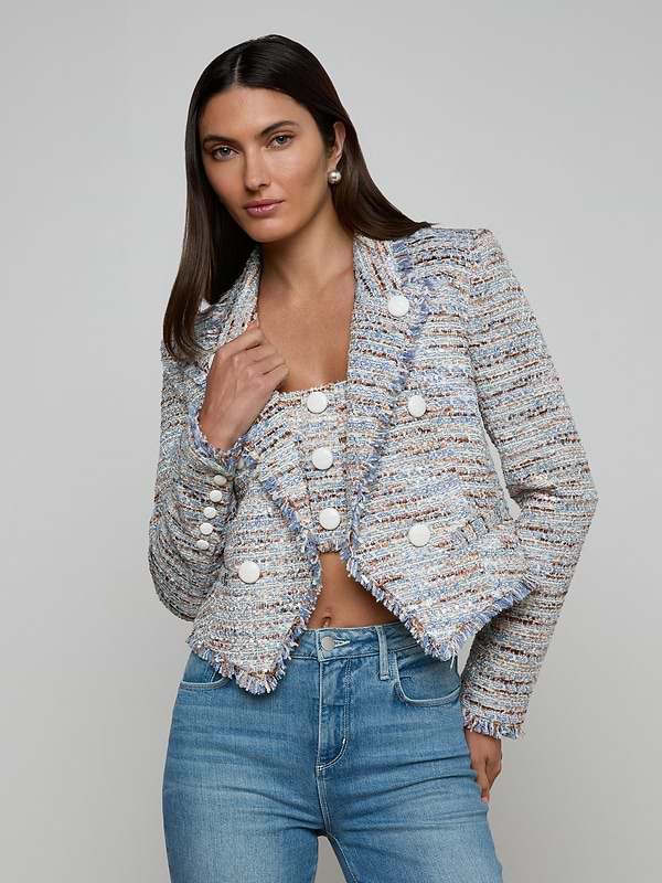A woman wearing the Marv Tweed Blazer—a textured, multicolored piece with statement buttons—paired with blue jeans stands against a plain light background, looking at the camera with a neutral expression.