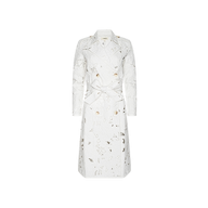 The Aman Trench Coat is a long white trench coat with a belted waist, tailored fit, classic collar, and an intricate cutout floral pattern. Debuted at Paris Fashion Week Spring 2027.
