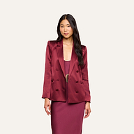 A woman with long dark hair wears the Sena Silk Blazer in merlot red over a matching maroon dress, standing against a plain, light background.