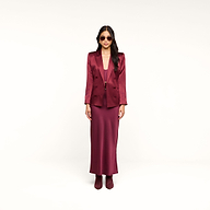 A woman stands against a white background wearing the Sena Silk Blazer in merlot red, paired with a matching long dress, burgundy boots, and sunglasses.