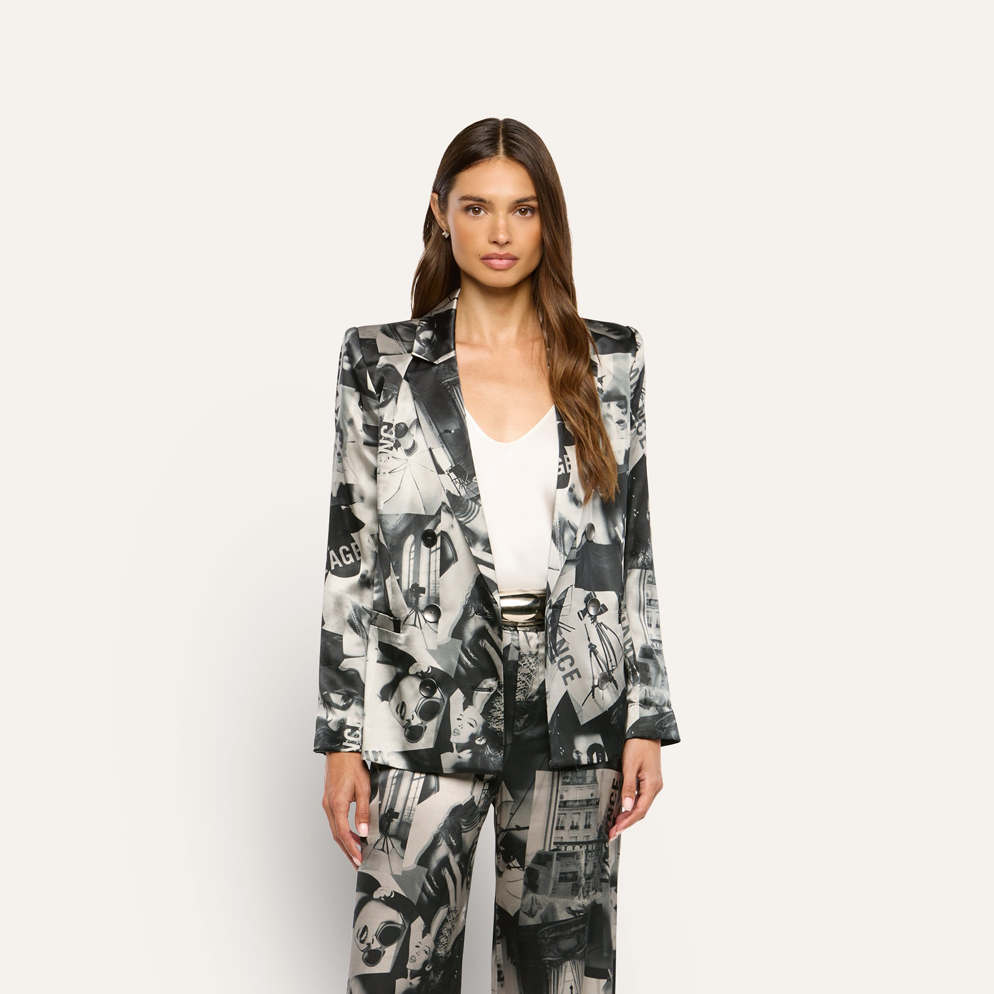 A person wearing a Sena Silk Blazer and matching trousers with a black-and-white collage print over a white top.