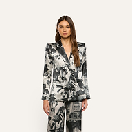 A person wearing a Sena Silk Blazer and matching trousers featuring a black-and-white collage print of text.