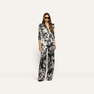 A woman wearing a Sena Silk Blazer with a statement print and matching wide-leg trousers, styled with oversized sunglasses.