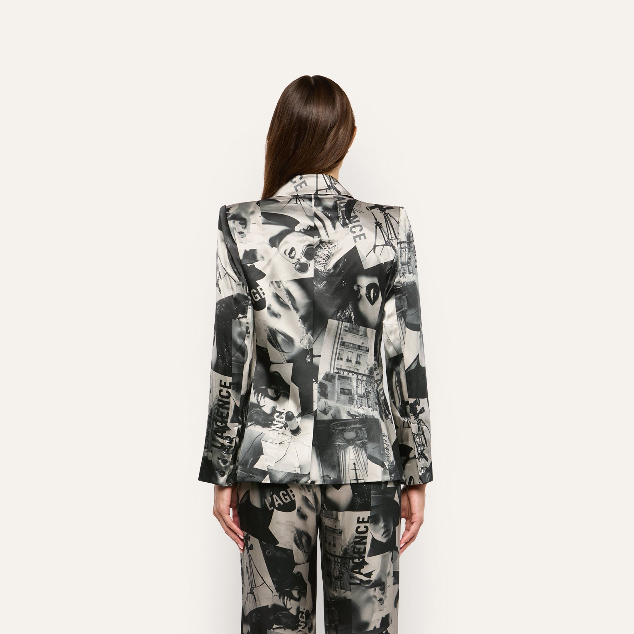 A person seen from behind wearing a Sena Silk Blazer and trousers featuring a black-and-white collage print with repeated text.