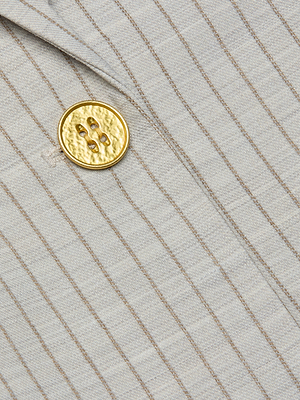 Close-up of the Sheila Longline Blazer in light gray pinstripe fabric, highlighting a single round textured gold button with four holes.