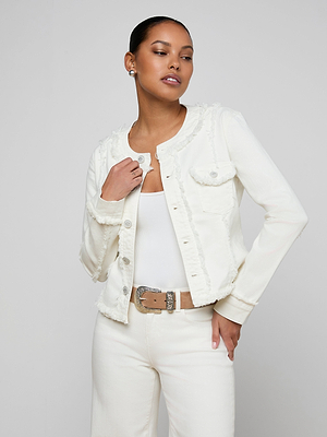 A woman stands confidently against a light gray background, posing with one hand on her Yarin Collarless Fray Jacket in off-white stretch denim, styled over a white top and off-white pants with a tan belt.