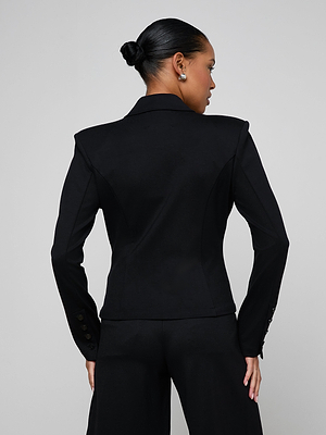 A woman with dark hair in a sleek bun models the Emerson Ponte Blazer and matching pants, standing with her back to the camera against a plain light gray background.