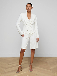 Styled in the Emerson Ponte Blazer—a tailored double-breasted design in white with silver buttons—this woman pairs it with matching knee-length super stretch ponte shorts and strappy high-heeled sandals, standing against a plain white background.