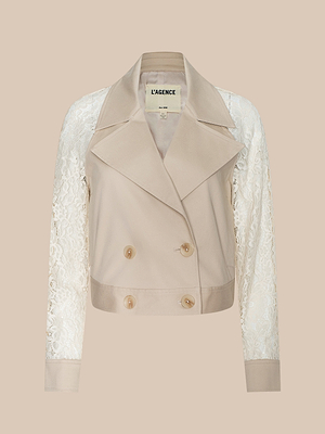 The Novelle Lace Trench is a beige cropped double-breasted jacket with wide lapels, cream lace sleeves, and four front buttons. This lightweight layer puts a modern spin on the trench coat style. The label inside reads LAGENCE.