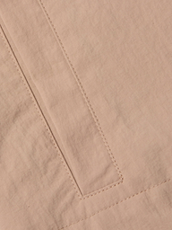A close-up of the beige nylon fabric of the Calida Windbreaker Trench highlights a rectangular sewn detail—possibly a pocket or seam—with visible stitching and slight creasing in its water-repellent material.