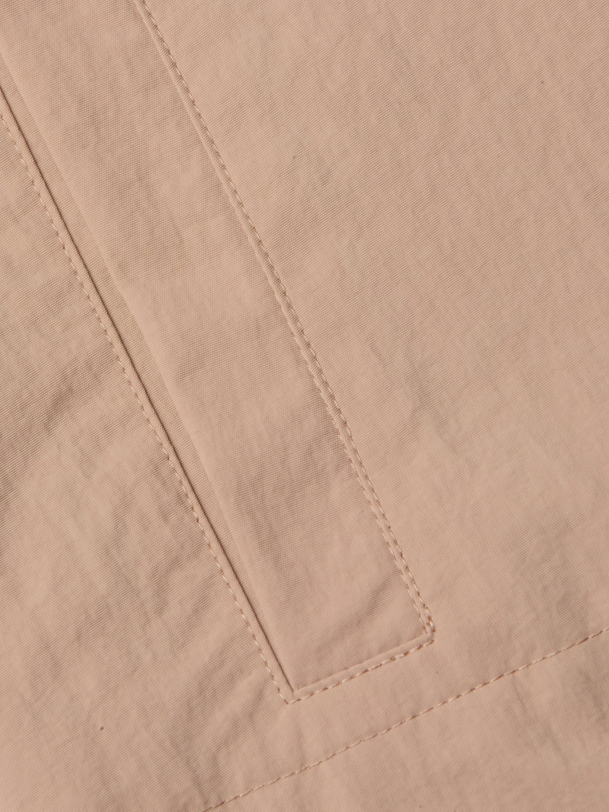 A close-up of the beige nylon fabric of the Calida Windbreaker Trench highlights a rectangular sewn detail—possibly a pocket or seam—with visible stitching and slight creasing in its water-repellent material.