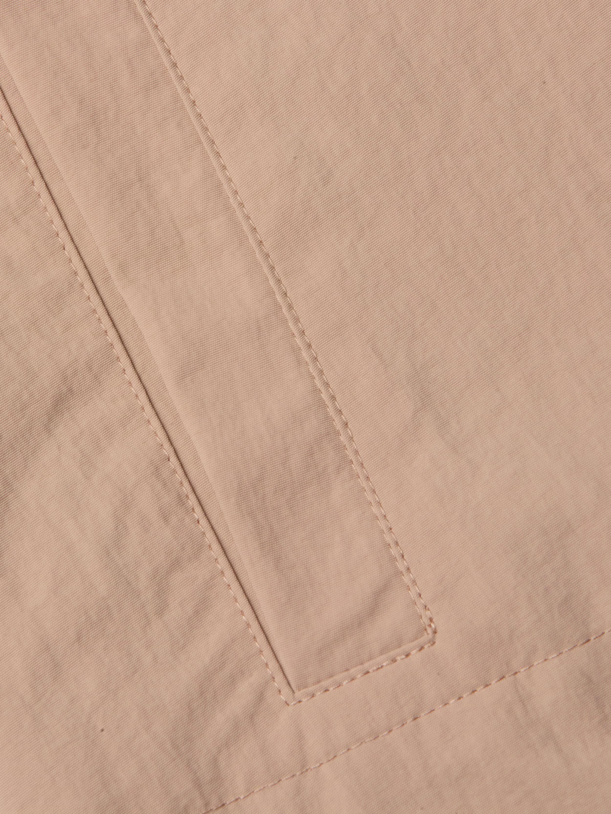 A close-up of the beige nylon fabric of the Calida Windbreaker Trench highlights a rectangular sewn detail—possibly a pocket or seam—with visible stitching and slight creasing in its water-repellent material.