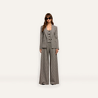 A person wearing a Blanche Blazer in a fitted houndstooth pattern, styled with a button-up vest, matching wide-leg trousers, and sunglasses.