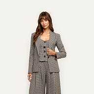 A person wearing a black and white houndstooth Blanche Blazer over a matching button-up vest and wide-leg trousers.