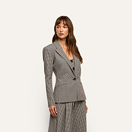 A woman wearing a black and white houndstooth Blanche Blazer over a matching scoop-neck top.