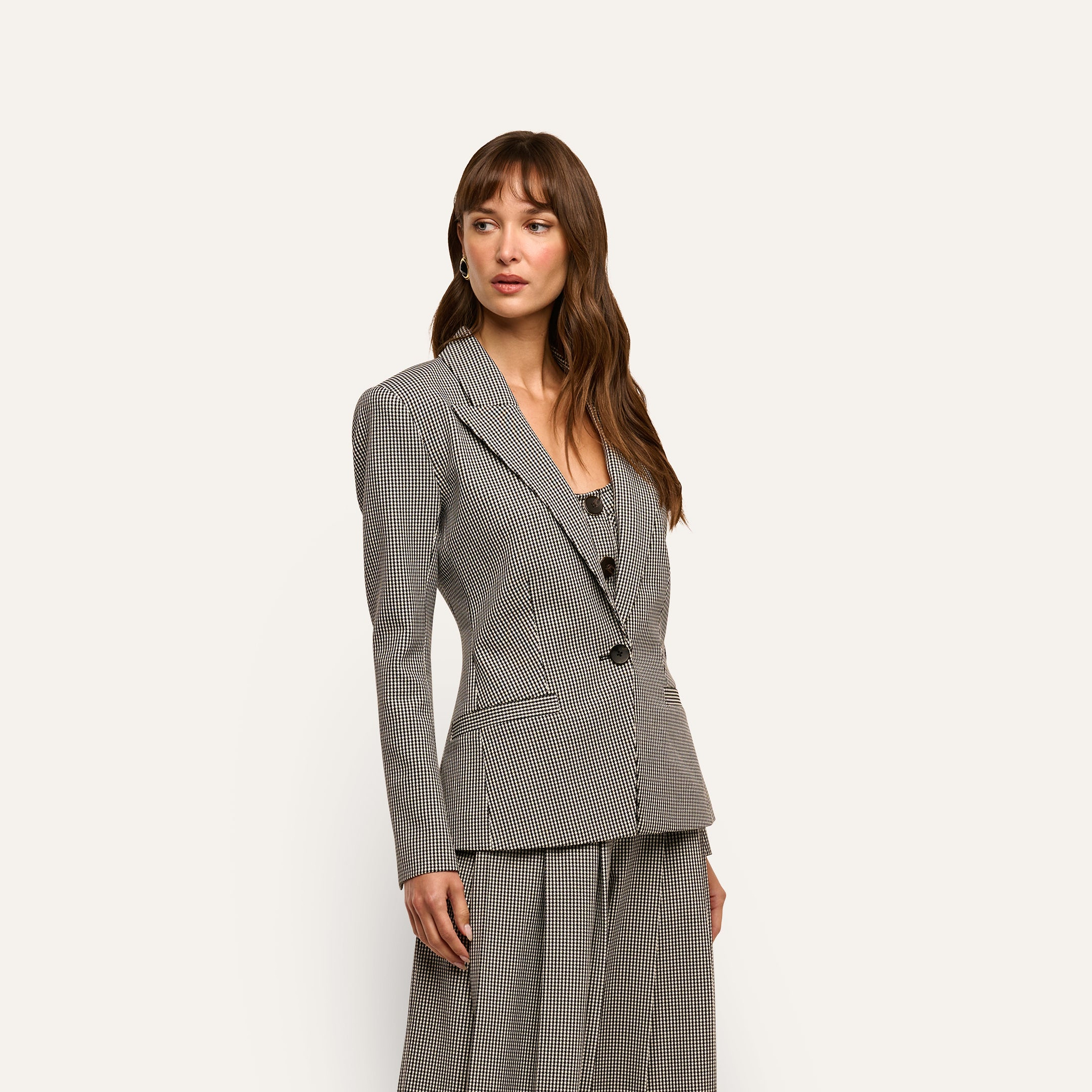 A woman wearing a black and white houndstooth Blanche Blazer over a matching scoop-neck top.