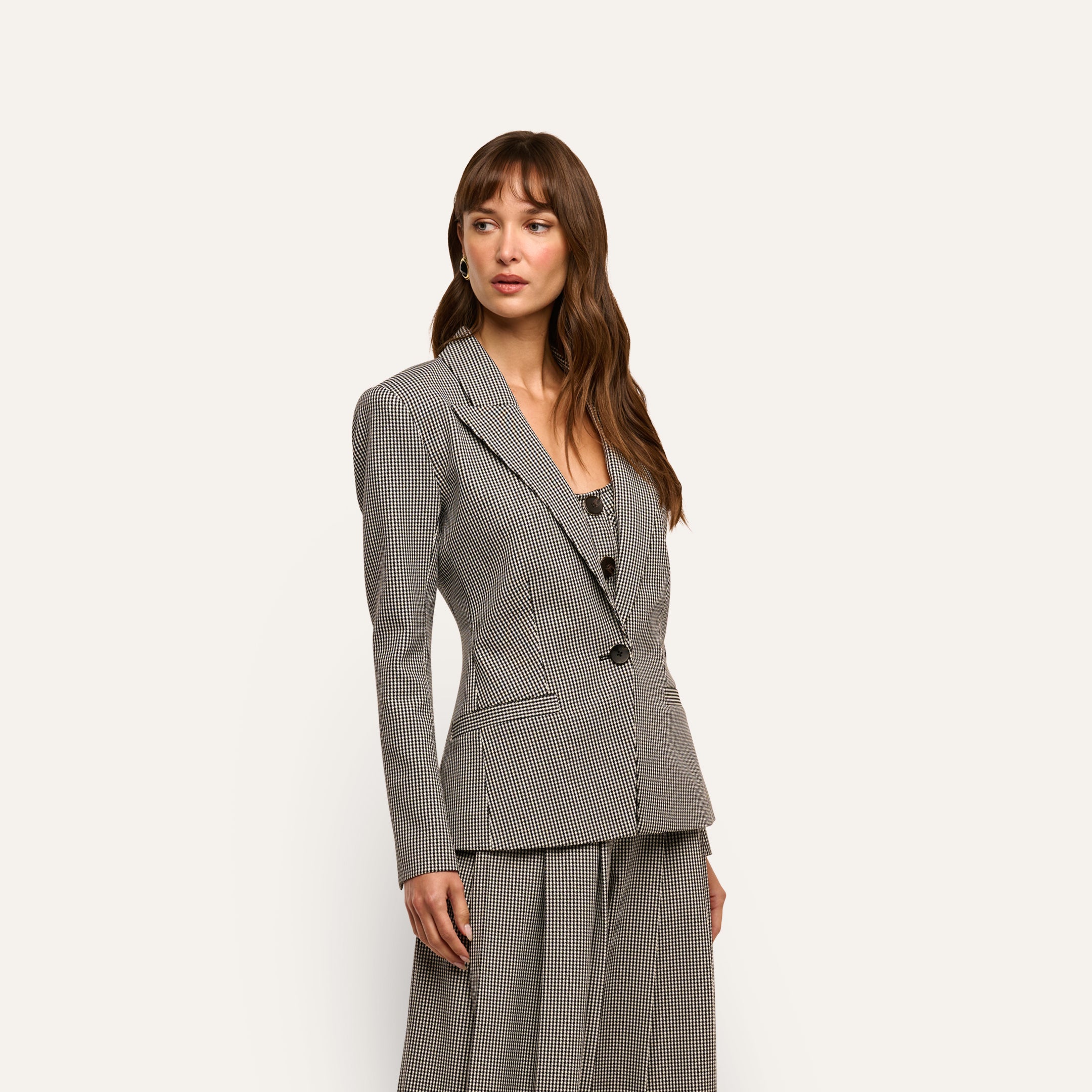 A woman wearing a black and white houndstooth Blanche Blazer over a matching scoop-neck top.