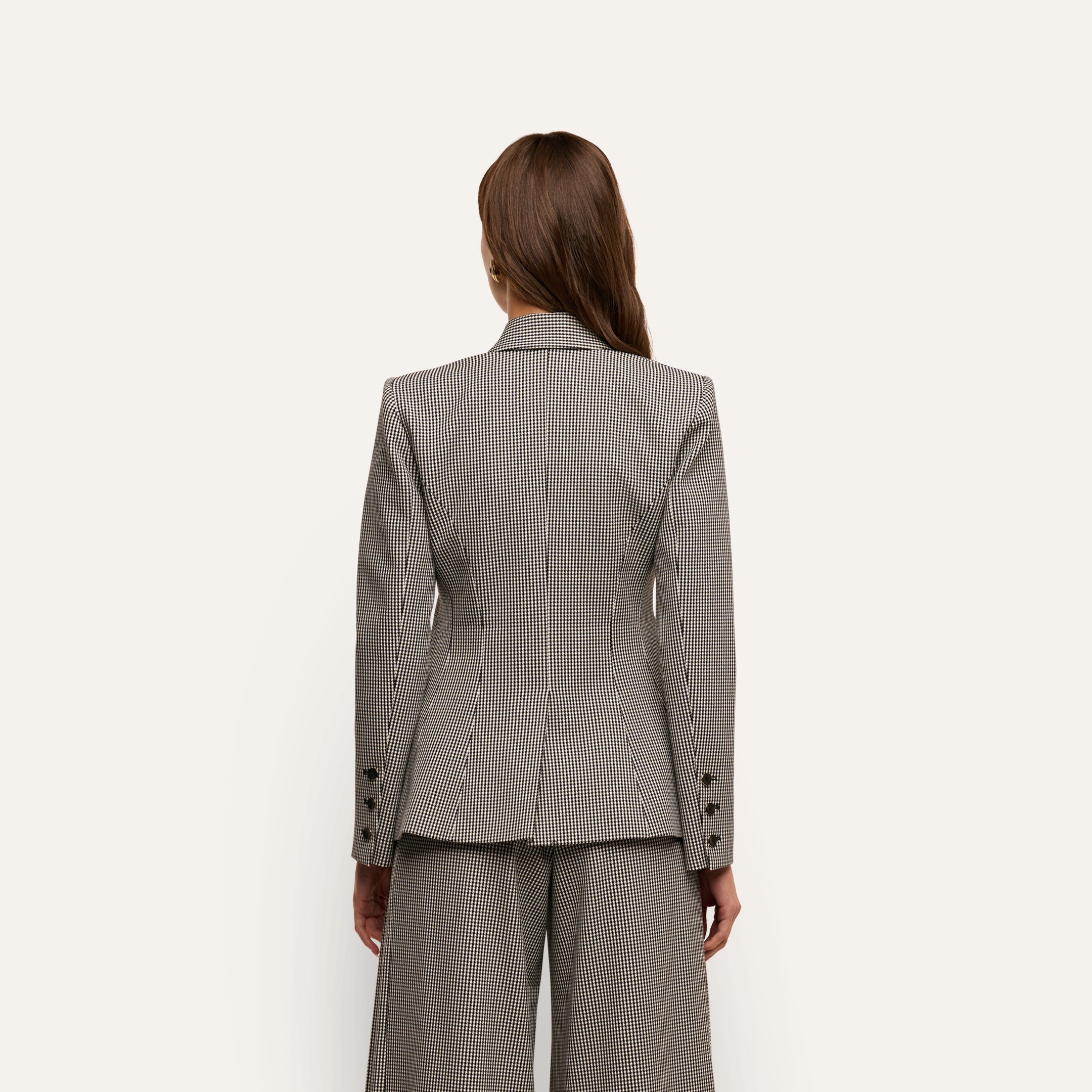 Back view of a person wearing a tailored, fitted houndstooth Blanche Blazer and matching trousers.
