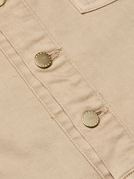 Close-up of beige fabric featuring two metallic buttons sewn in a diagonal line, highlighting the visible stitching and textured detailing characteristic of the Kirstie Jean Shirt Jacket.