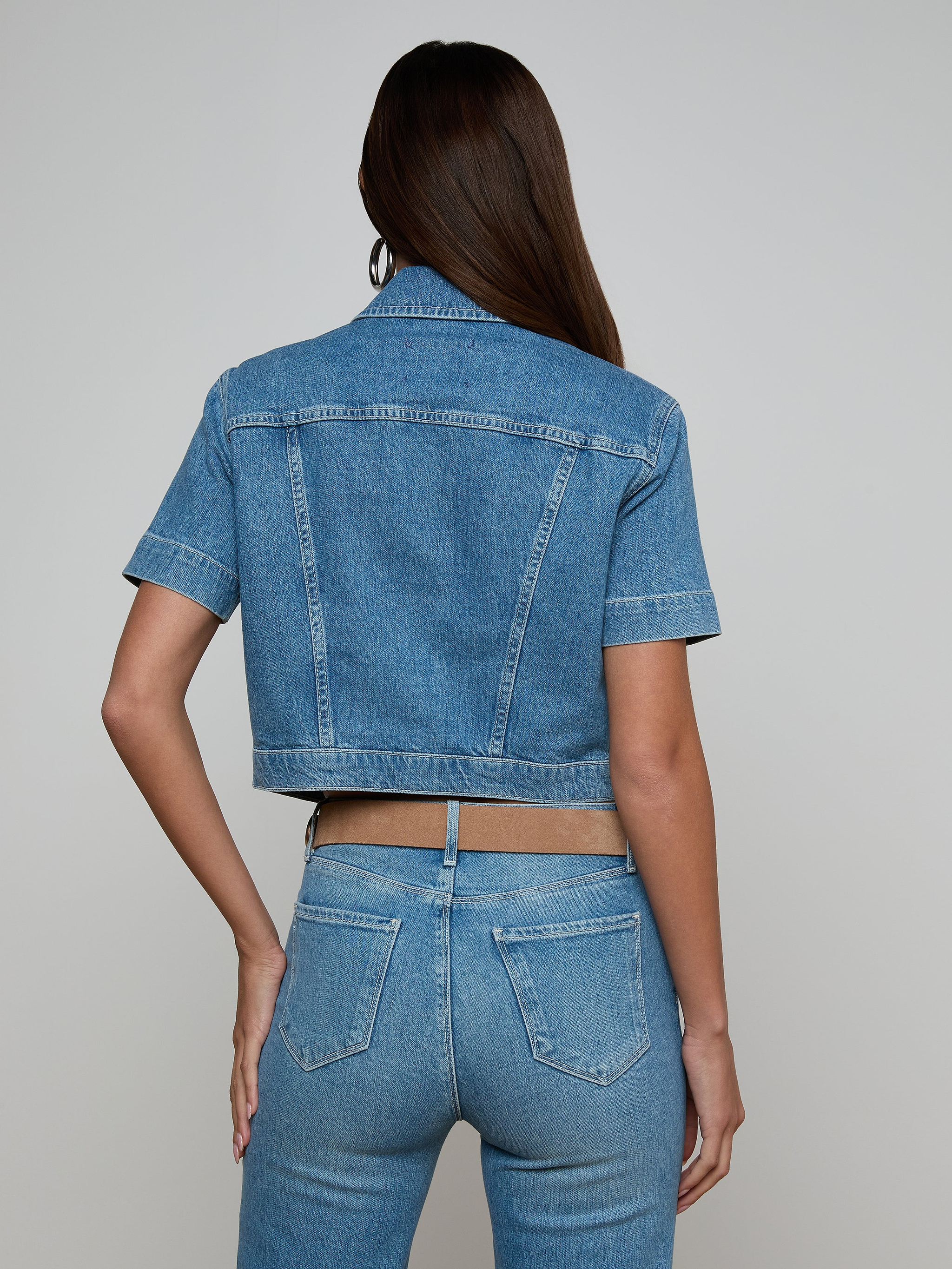 A woman with long brown hair is shown from the back, wearing the Kirstie Jean Shirt Jacket and high-waisted blue jeans against a plain light background.
