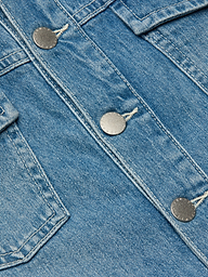 Close-up of blue denim fabric with metallic buttons and visible stitching, highlighting a section of the Kirstie Jean Shirt Jacket.