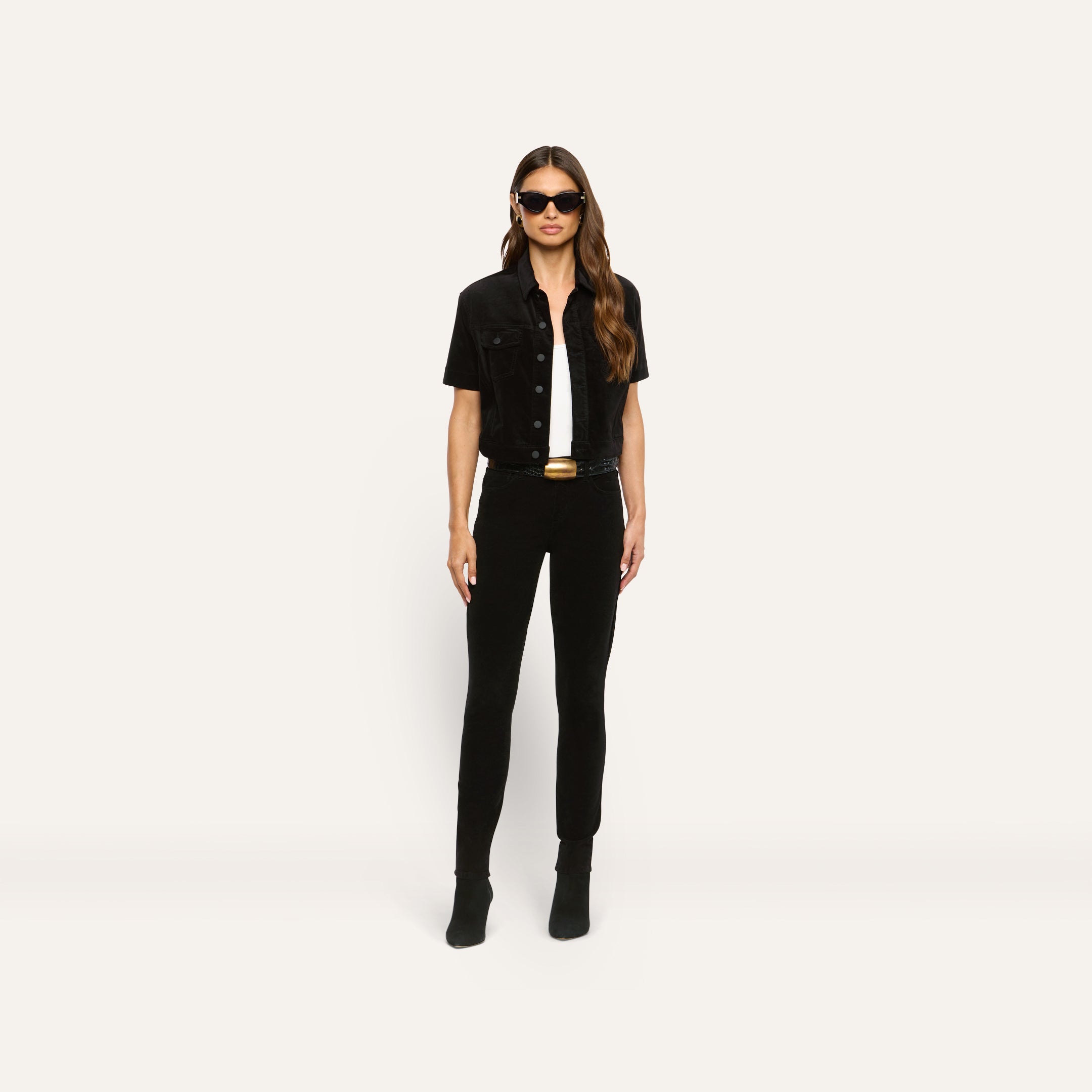 A model wearing a black velvet Kirstie Velvet Shirt Jacket over a white top and black pants, accessorized with a black belt and sunglasses.