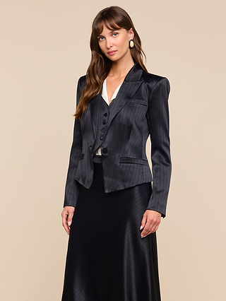 A woman with long brown hair, wearing the Misa Blazer, matching vest, and a black satin suiting skirt, stands against a beige background looking at the camera.