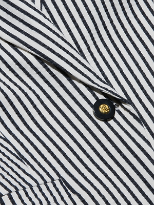 Close-up of the Misa Seersucker Blazer, a black and white striped jacket featuring a gold and black button and a pointed lapel.