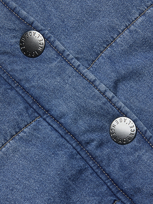 Close-up of indigo denim fabric with two embossed metallic buttons and visible stitching, showcasing the detailed texture ideal for the Rola Puffer Vest in a cropped length.