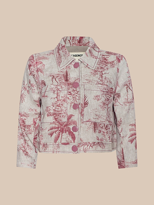 The Eda Cropped Linen Jacket is a light-colored, long-sleeve jacket with a pink toile scenic print, button closure, chest pockets, and a classic collar, shown against a plain beige background.